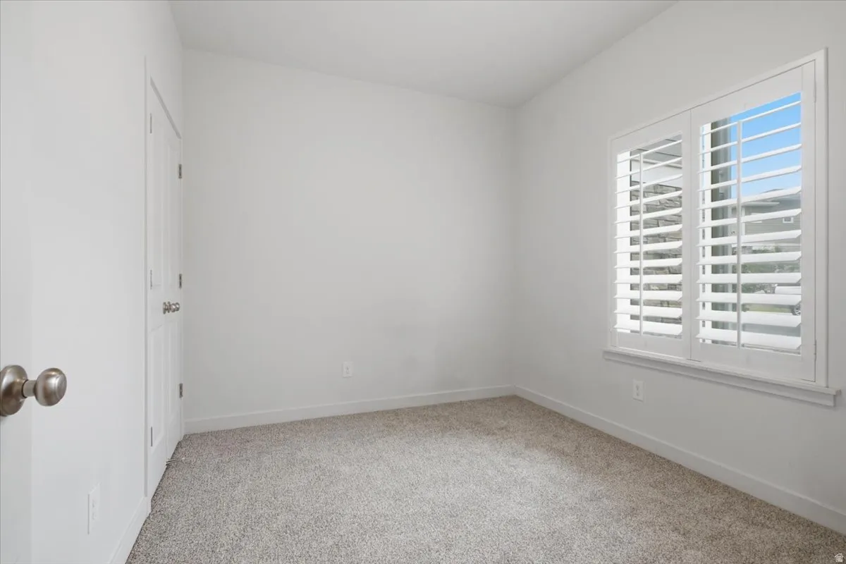 White painted walls, white plantation shutters, and carpeted flooring