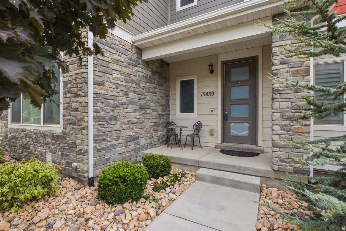 Stone veneer facade with siding accents, covered entry, and concrete walkway