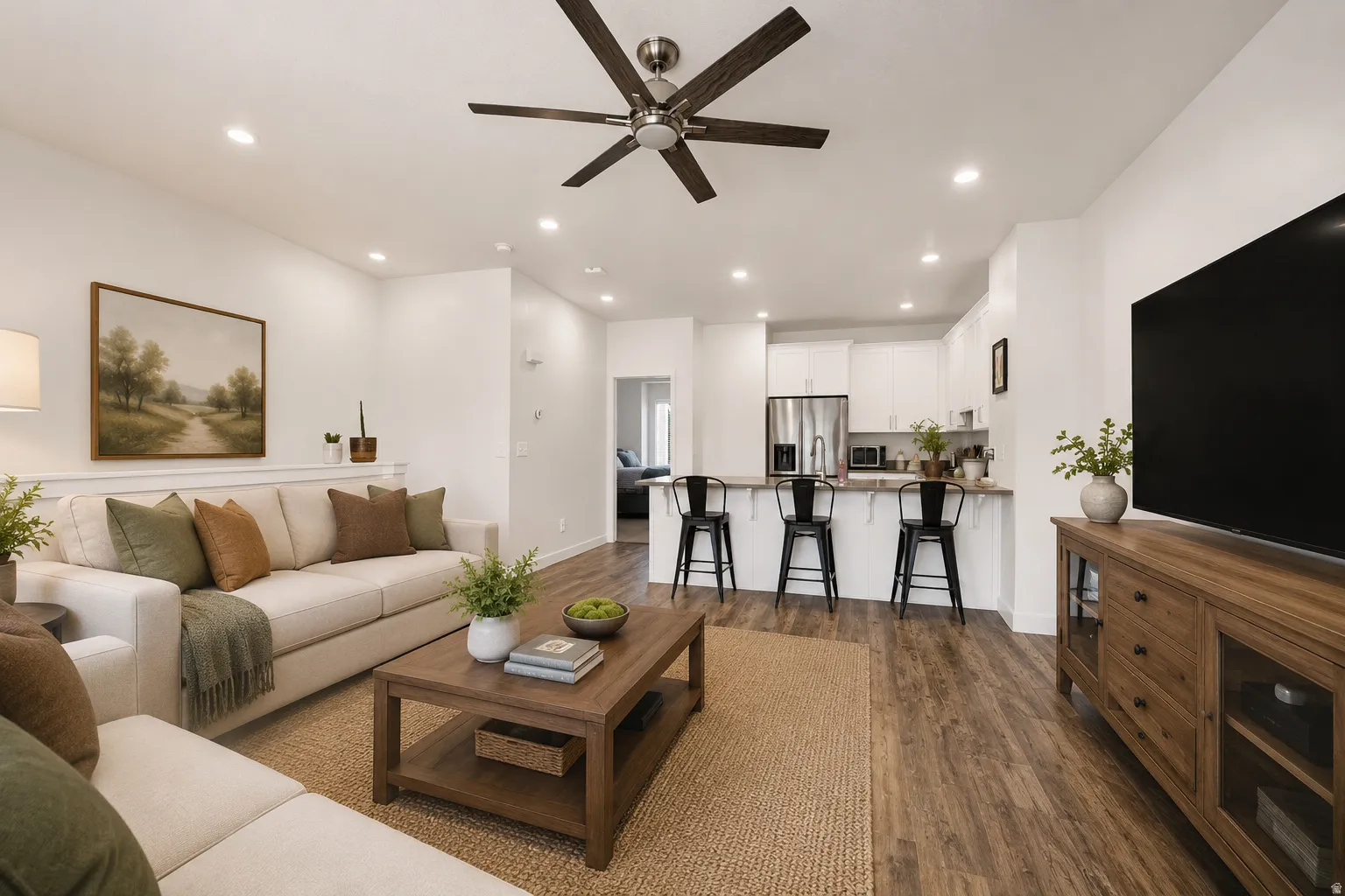 Open-concept living space featuring wood-finish flooring, recessed lighting, a ceiling fan, and a kitchen island with seating