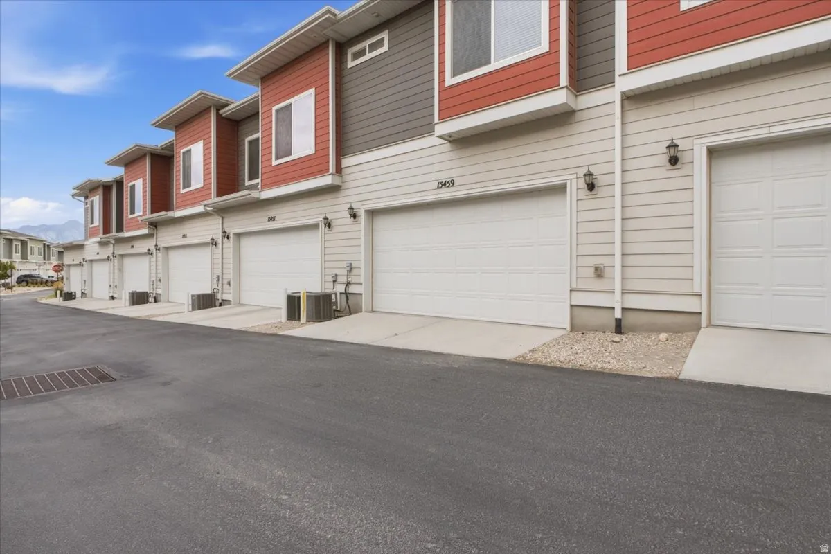 Contemporary townhome exterior with red and grey siding, attached garages, and a paved driveway