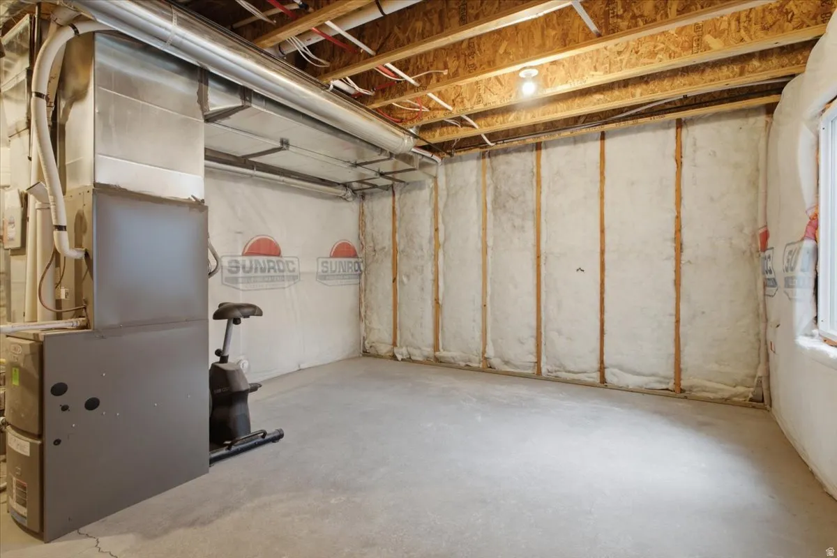 Unfinished basement featuring exposed wood joists, concrete flooring, and insulated walls