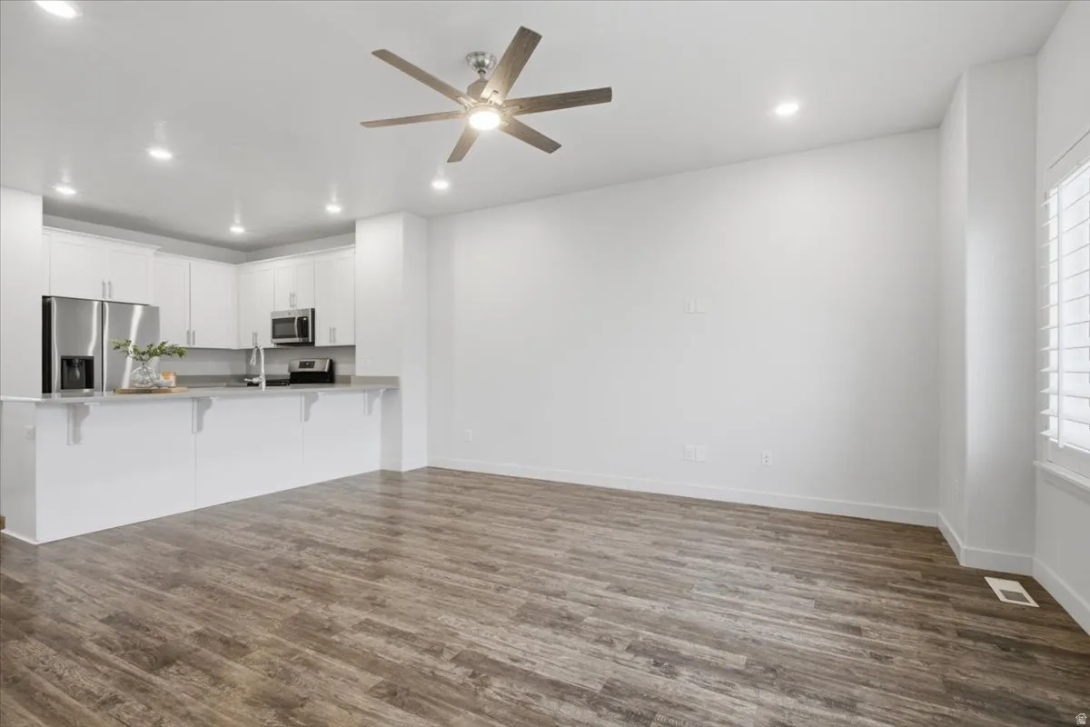 Open-concept living space with wood-finish flooring, recessed lighting, and a ceiling fan