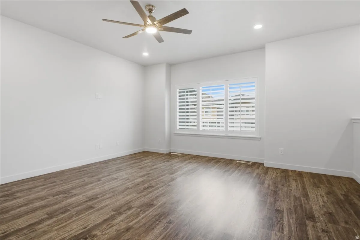 Bright room featuring wood-finish flooring, white walls, and a ceiling fan with integrated lighting