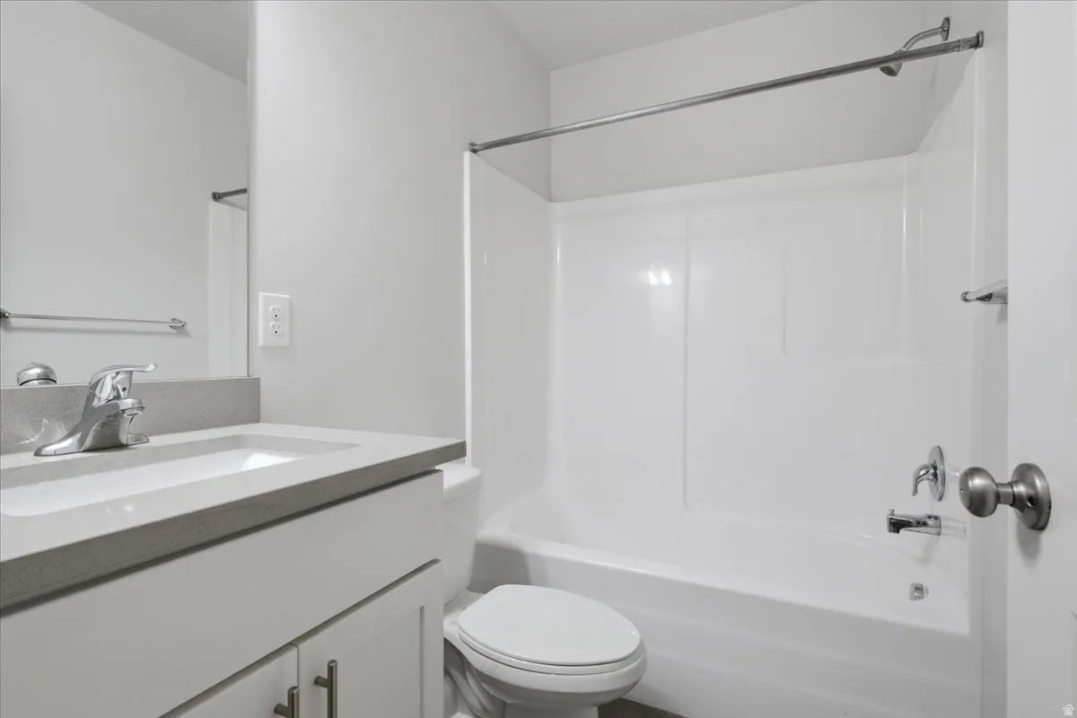 Modern vanity with a gray countertop and integrated sink, chrome faucet, and white cabinetry