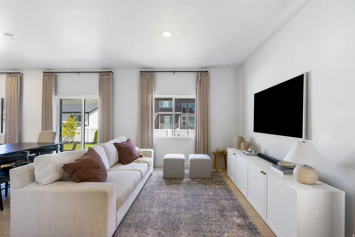 Open-concept living area featuring light wood-finish flooring, recessed lighting, and a white built-in media console with cabinet storage