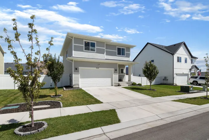 Two-story residence featuring light gray siding, an attached two-car garage, and a concrete driveway