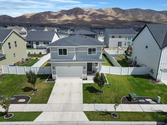 Contemporary two-story residence featuring a front-facing garage, a concrete driveway, and a white privacy fence