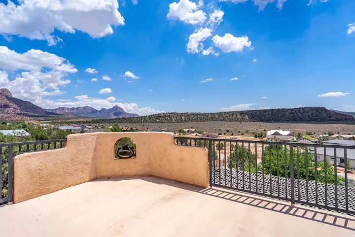 Outdoor patio featuring a stucco parapet wall with an arched niche, a durable railing, and a desert landscape
