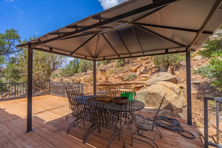Expansive outdoor deck with a metal gazebo, wood plank flooring, and dark metal railings