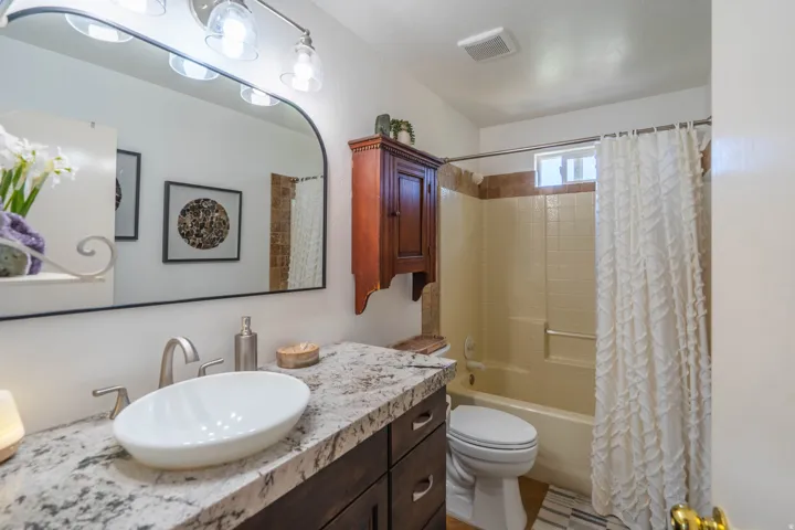 Vanity with granite-style countertop, vessel sink, and brushed nickel faucet