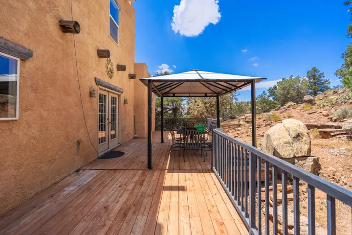 Expansive wood deck with metal railing, adjacent to a stucco exterior with exposed wood beams and double French doors