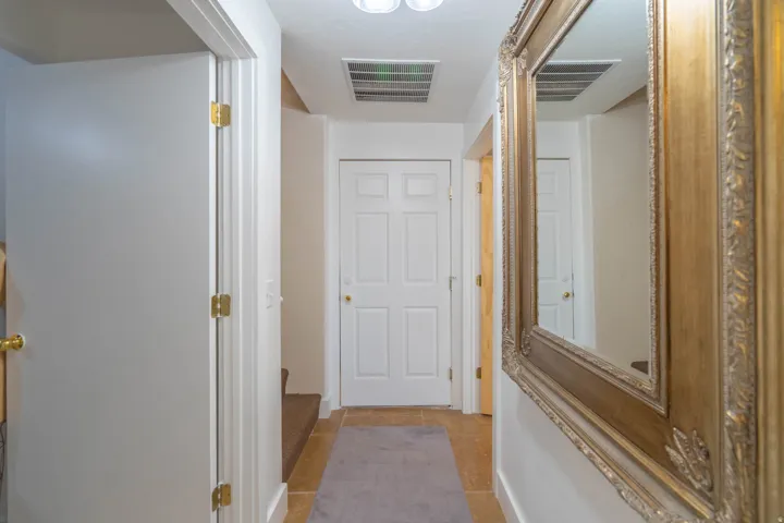 Hallway featuring tile flooring, white paneled doors, and a decorative framed mirror