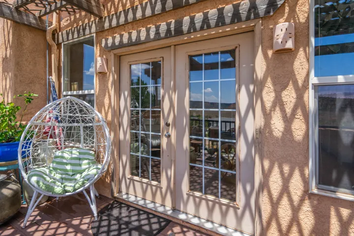Covered patio with decorative lattice pergola and geometric shade patterns, featuring French doors with multi-pane glass panels and sightlines to the surrounding landscape
