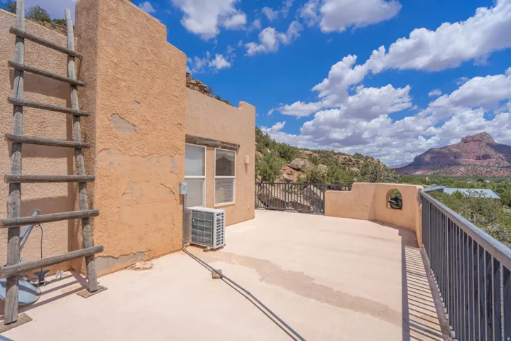 Stucco exterior, flat roof, wood ladder, outdoor railing, and window