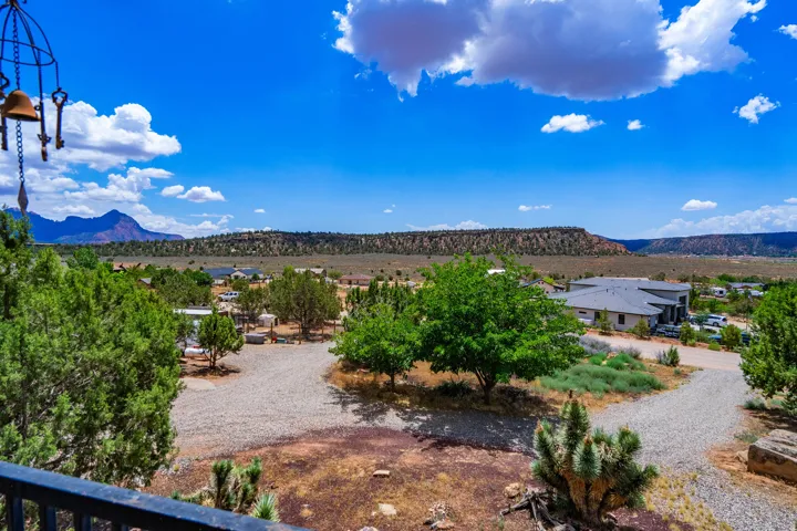 Expansive landscape featuring distant mountains, a gravel driveway, and mature trees