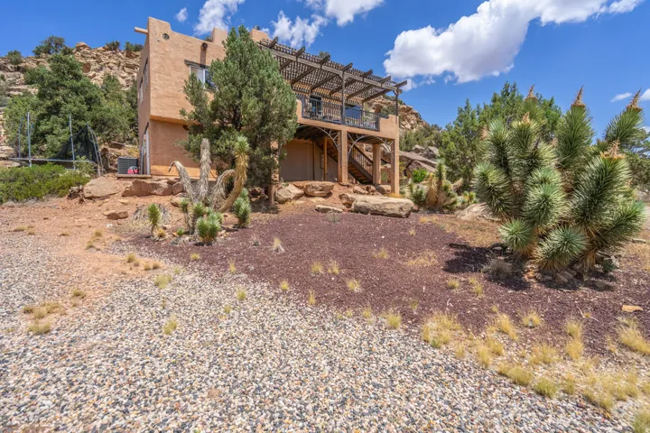 Southwestern exterior with a built-in balcony, wood pergola, and decorative metal railings