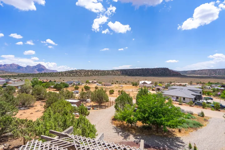 Sprawling rural property featuring mature landscaping with established trees, multiple residential structures, and expansive grounds set against dramatic mesa backdrop under clear Arizona skies