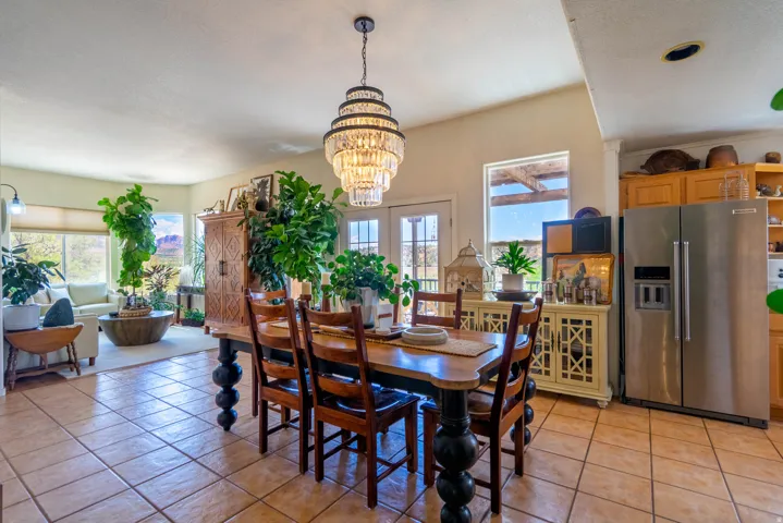 Neutral-toned tile flooring extends throughout the space, complemented by a tiered chandelier with crystal accents