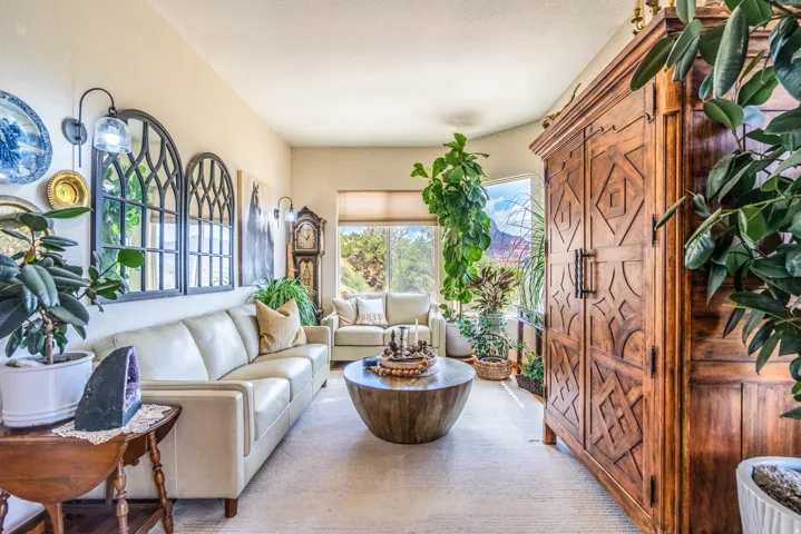 Warm living space featuring a light-toned sofa, arched wall decor with sconce lighting, and a large window with natural light