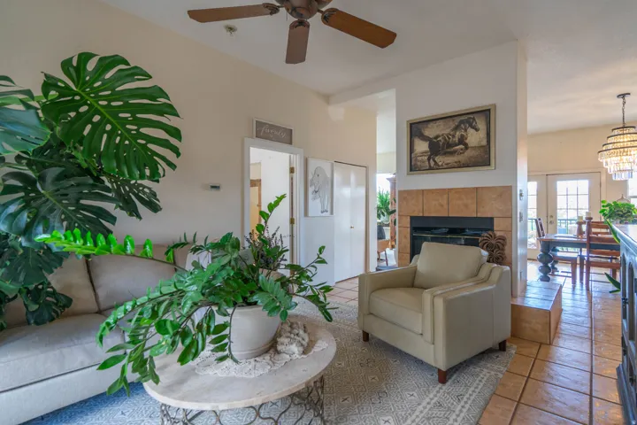Living area featuring a ceiling fan, tiled fireplace surround, and recessed entryway