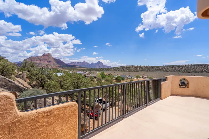 Terrace with stucco wall, metal railing, and a desert landscape backdrop