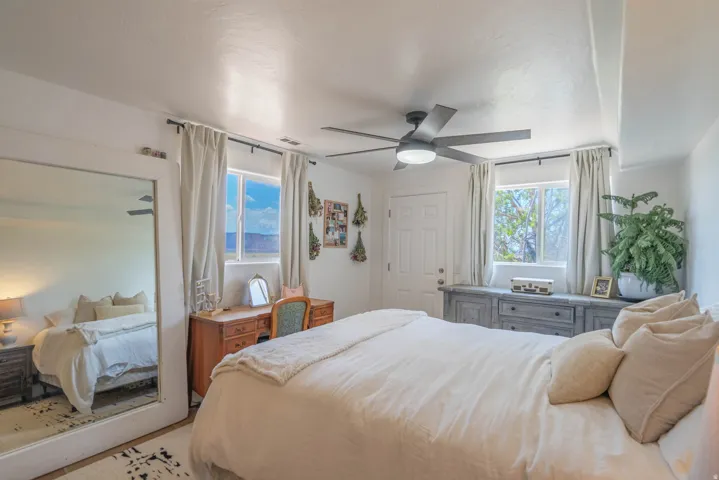 Ceiling fan with integrated lighting, two windows with drapery, a built-in wood-finish cabinet, and a door with paneling