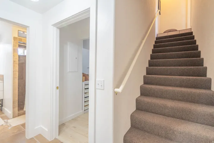 Bright entryway with clean white trim and neutral finishes, featuring a staircase with carpeted treads and a handrail, direct access to additional rooms, and recessed ceiling lighting