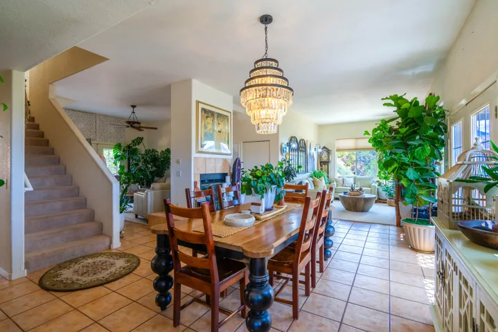 Open-concept living space featuring a tiered crystal chandelier, tile flooring, and a fireplace with a tile surround