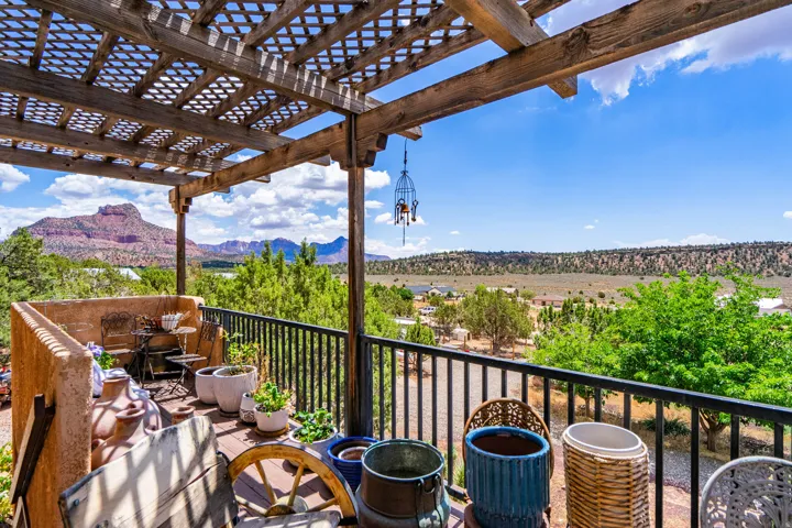 Expansive outdoor deck with a lattice pergola, black metal railing, and a plaster wall