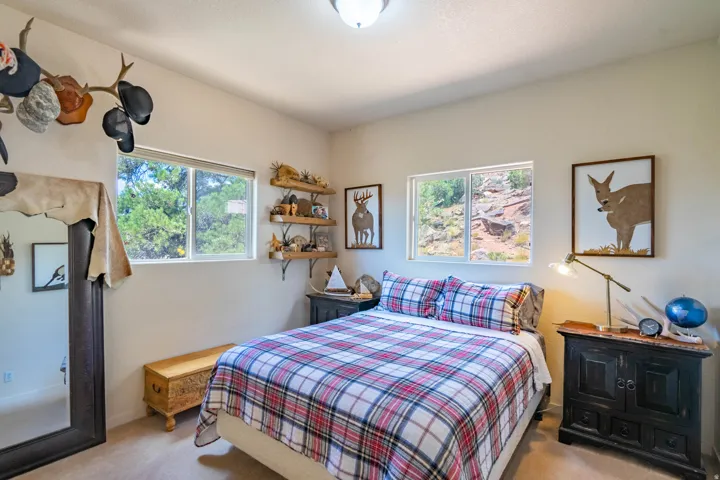 Recessed ceiling light fixture, twin windows providing natural light, wall-mounted open shelving, and a large floor mirror