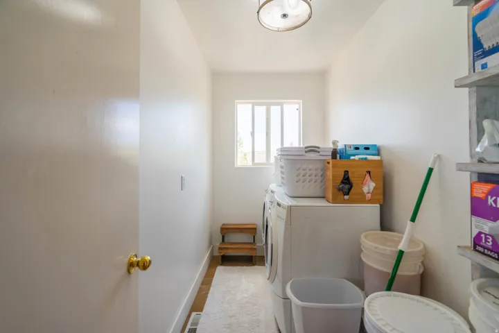 Laundry area with a fixed window, wood-finish flooring, and a flush-mount light fixture