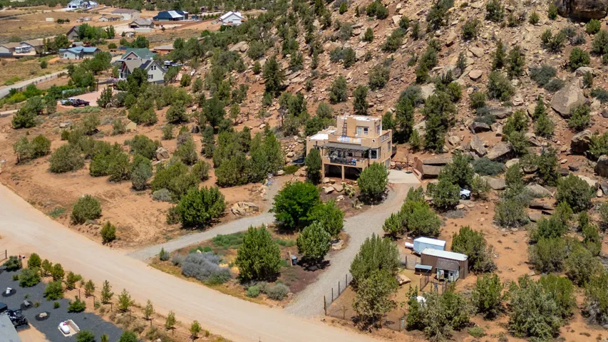 Aerial view showcasing a custom residence nestled on a generously proportioned lot with mature tree coverage, a defined driveway approach, and a resort-style pool area surrounded by natural landscape