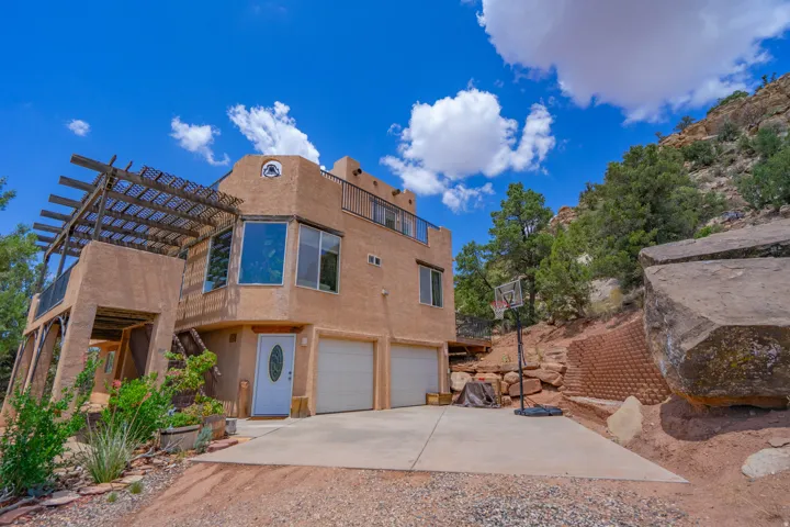 Stucco exterior with a two-car garage, multiple upper-level balconies, and a wood pergola
