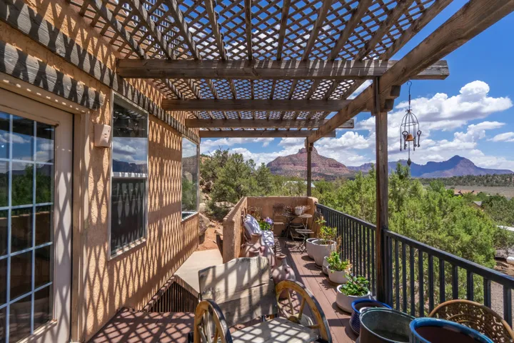 Covered patio with lattice pergola and metal railing overlooking manicured grounds and mountain backdrop