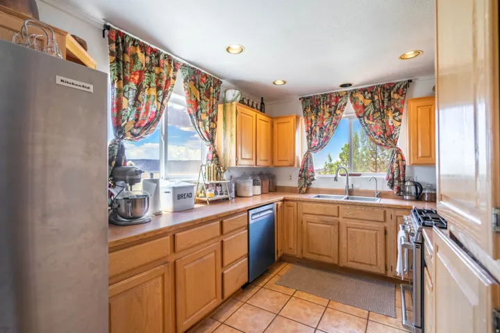 Kitchen featuring wood cabinetry, tile flooring, recessed lighting, and a double basin sink