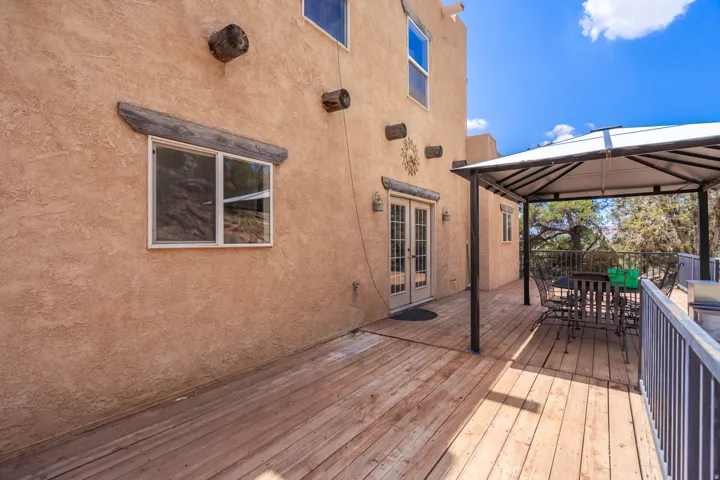 Exterior featuring a stucco facade, wood deck, double French doors, and a covered gazebo structure
