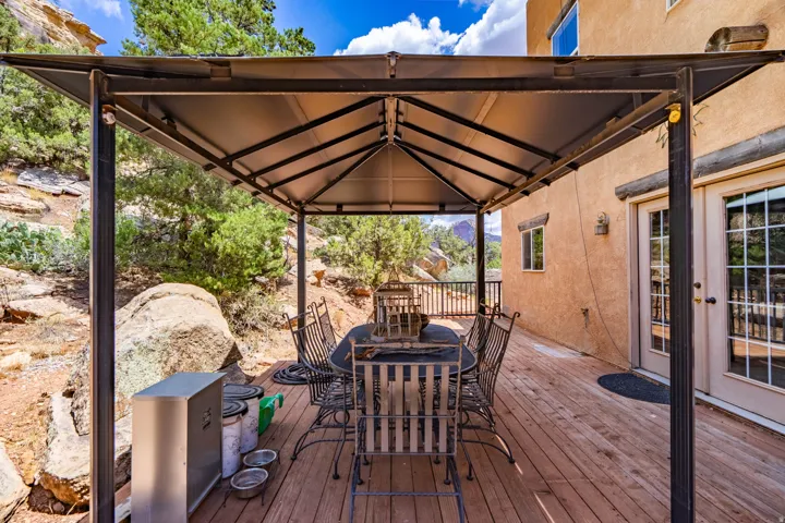 Covered patio with steel frame structure and peaked roof design, featuring composite wood-finish decking and direct access to the residence
