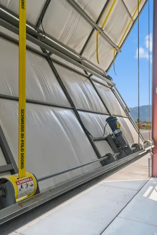 Bi-fold door system with a robust metal frame, white paneling, and an exposed motor mechanism