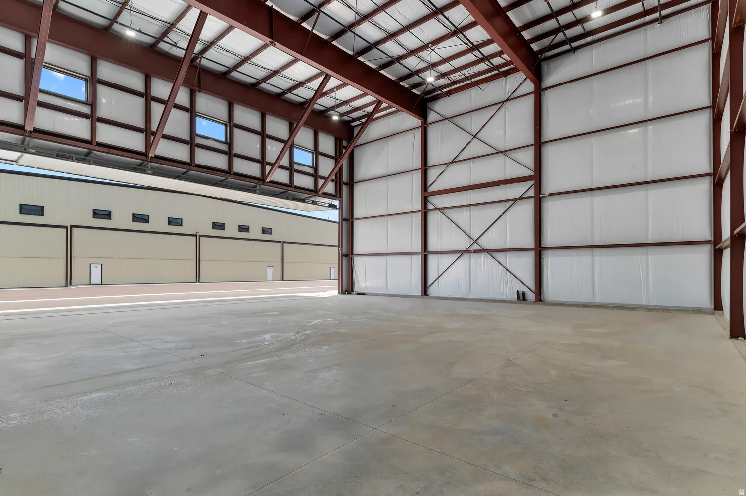 Large open industrial space featuring a concrete floor, exposed metal structural beams, and overhead lighting