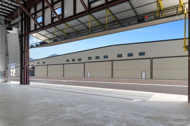 Industrial structure with a large open bay door, exposed steel beam construction, and a concrete floor