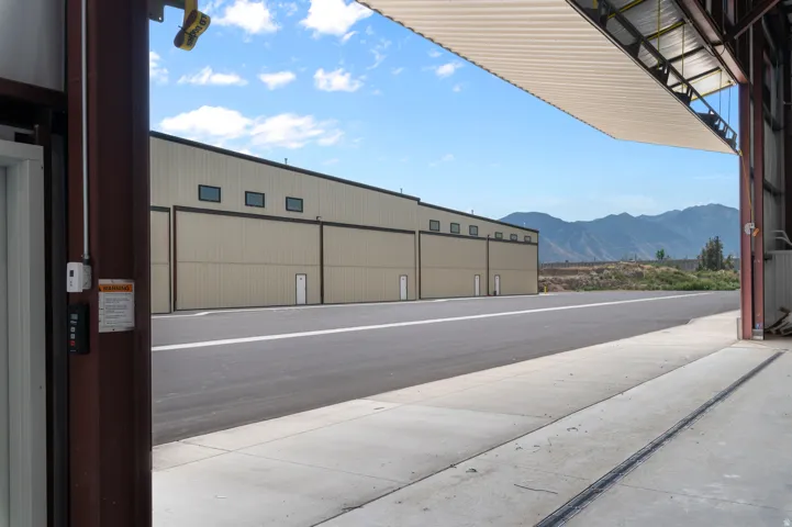 Large metal structure with an open hangar door, concrete flooring, and an asphalt landing surface