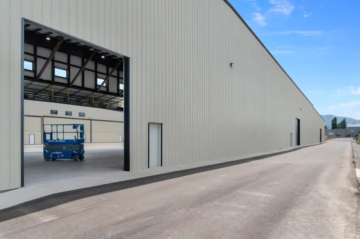 Large industrial building featuring a wide entry bay, multiple personnel doors, and durable corrugated metal siding