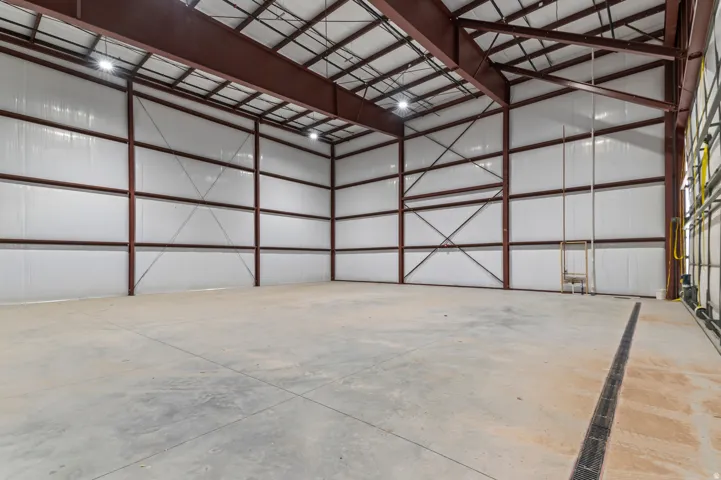 Expansive warehouse space featuring exposed structural beams, high ceilings, polished concrete flooring, and ample overhead lighting