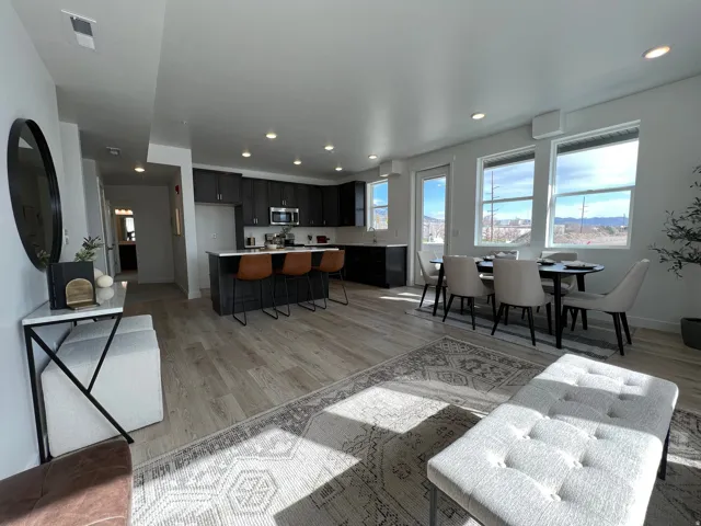 Open-concept living space featuring wood-finish flooring, recessed ceiling lighting, and expansive windows with natural light