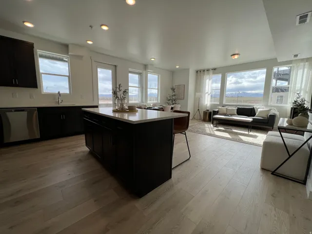 Open-concept living space featuring wood-finish flooring, recessed lighting, and a kitchen island with a light-toned countertop