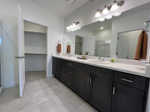 Dual vanity with dark wood-finish cabinetry, integrated sinks, and a full-width mirror