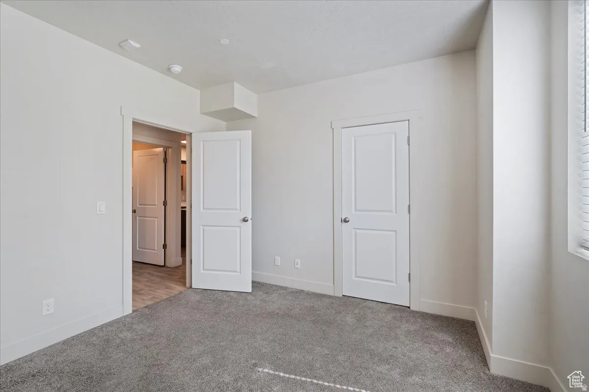 Neutral wall paint, plush carpeting, white trim, and a window with blinds