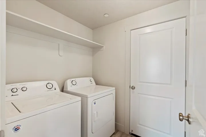 Dedicated laundry space featuring a white shelf, light wood-finish flooring, and a white panel door