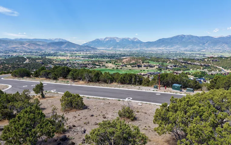 Paved road with marked turnarounds, surrounded by natural landscaping, offering expansive mountain scenery