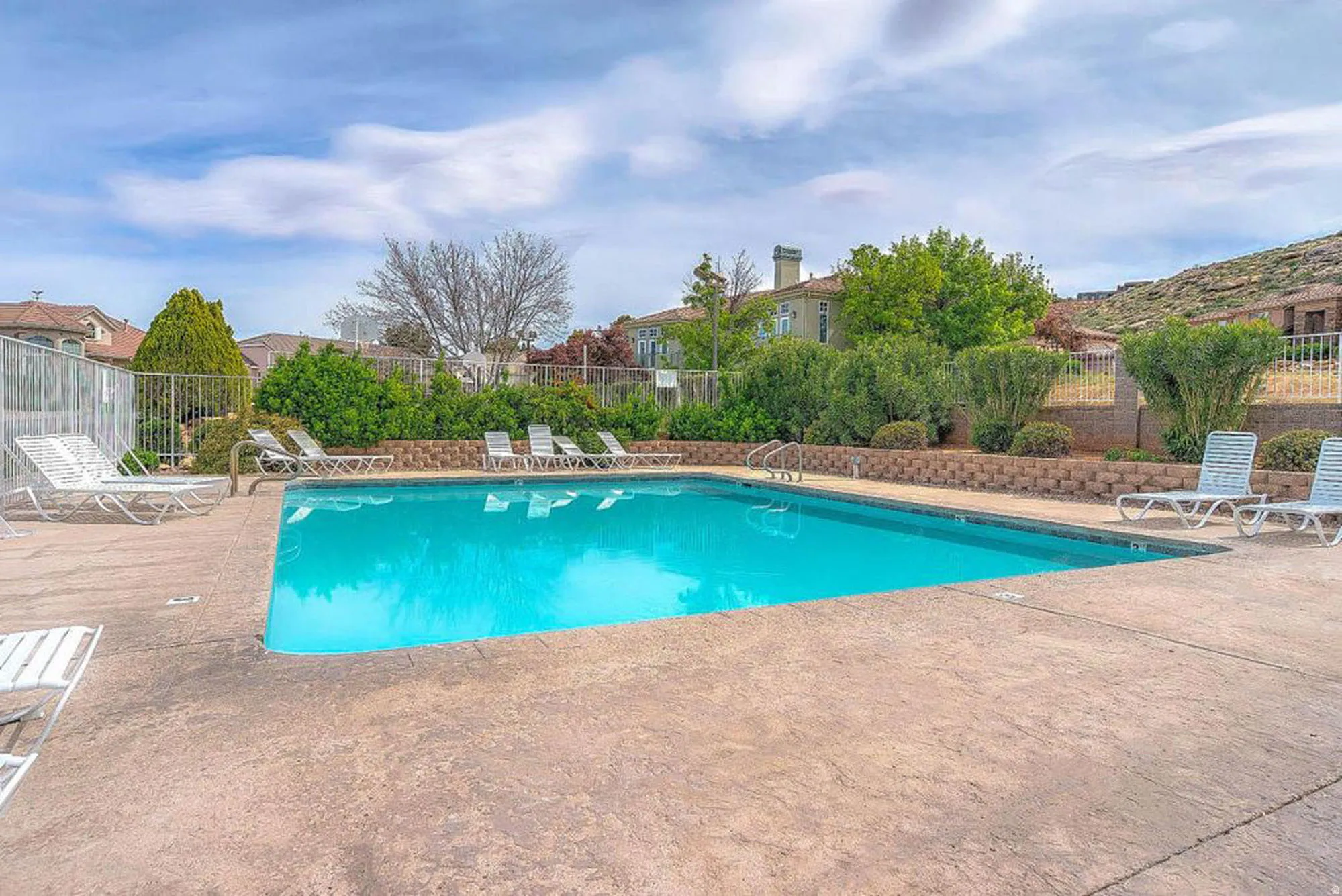 Resort-style swimming pool featuring crystal-clear turquoise water, concrete decking, and integrated lounge seating areas